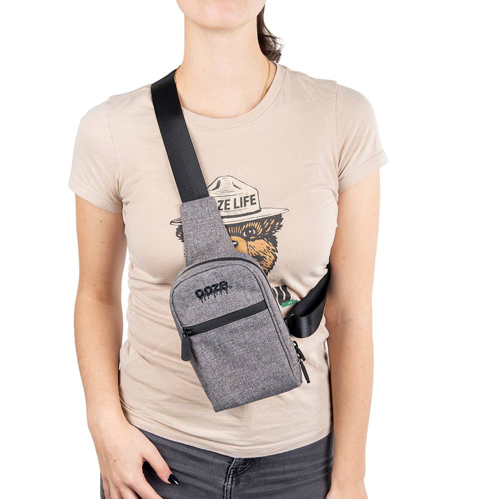 A girl is wearing the smoke grey Ooze crossbody bag across her chest