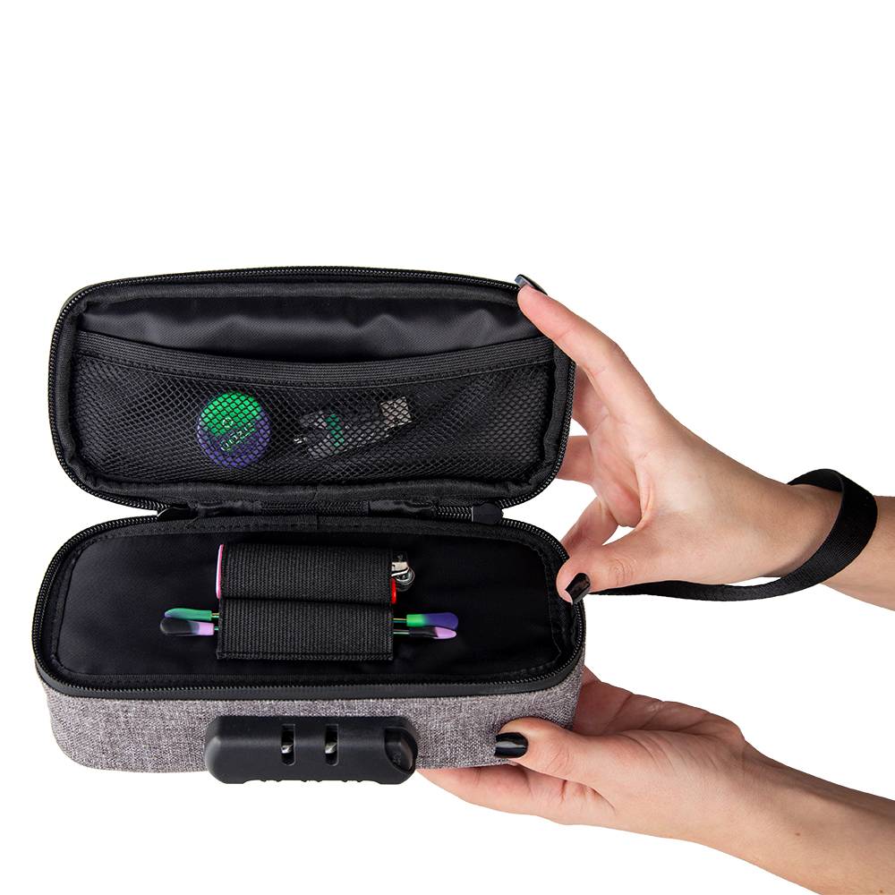 A girl with black nails holds the smoke grey Ooze travel pouch open to show the dab tools, lighter, stash jar, and charger stored inside.