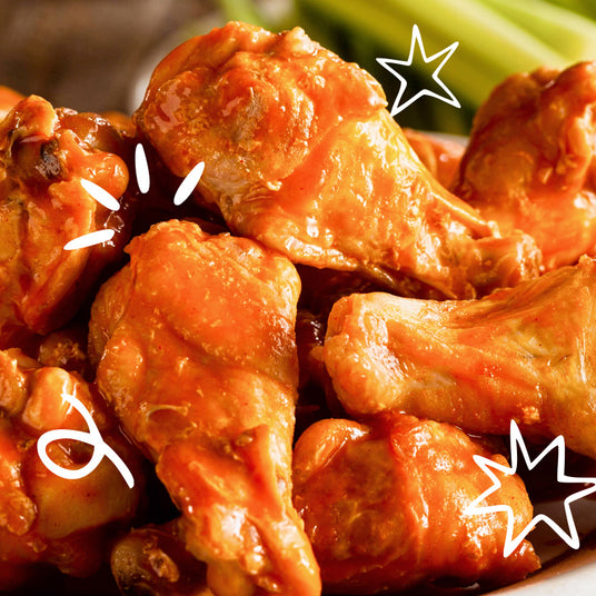 Pile of Freshly Made Ooze Blazed Buffalo Wings with THC Hot Sauce on a plate with white cartoon doodles and stars around the sides.