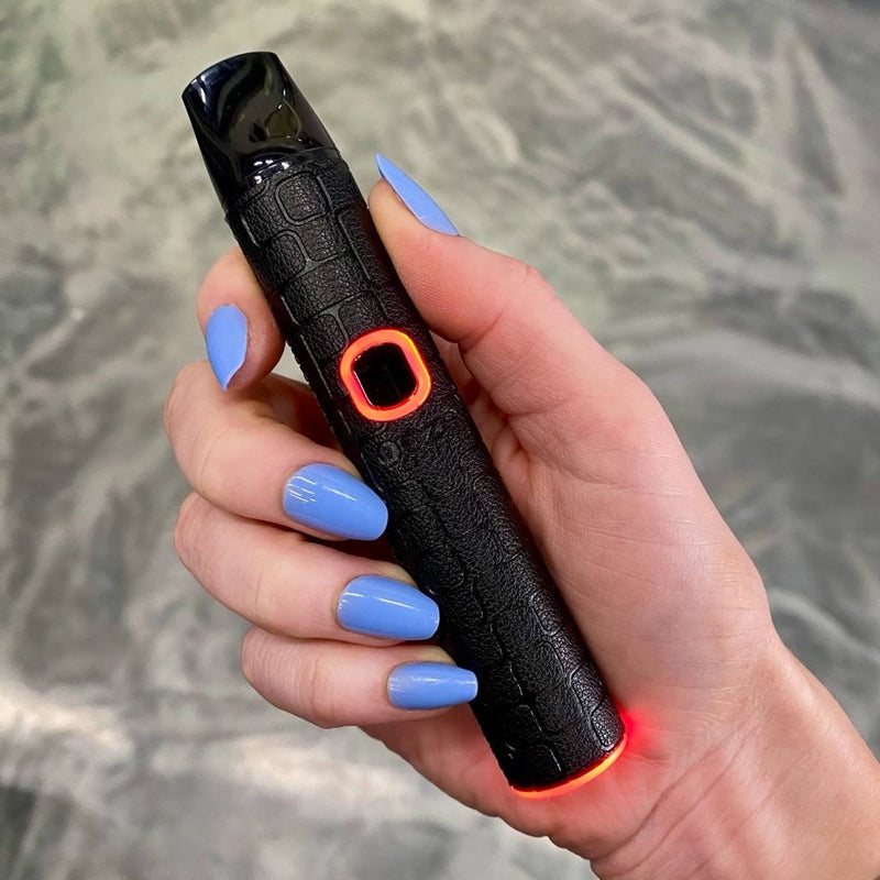 Hand holding a black Pinch dry herb vape device with a textured grip, against a neutral background.