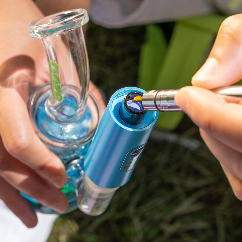 Loading a dab into a blue Booster extract vape that's attached to a bong with a twist hot knife