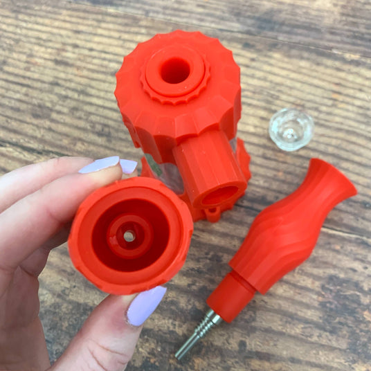 The scarlet Ooze Clobb silicone bong is completely disassembled. The armor bowl is held up to show where to insert a vape pen