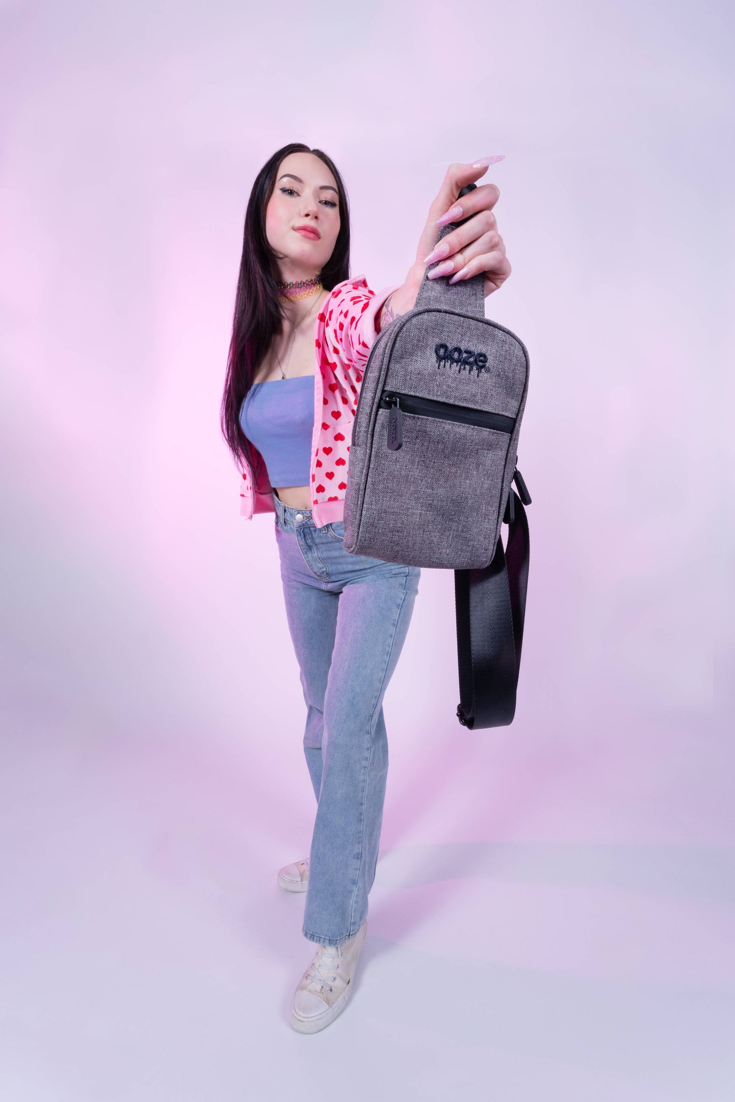 A girl is holding out the smoke grey Ooze crossbody bag