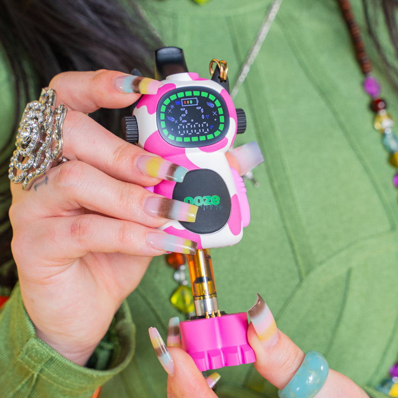 Pulling the base out of a pink cow Ooze Bot vape to show the 510 cartrige inside
