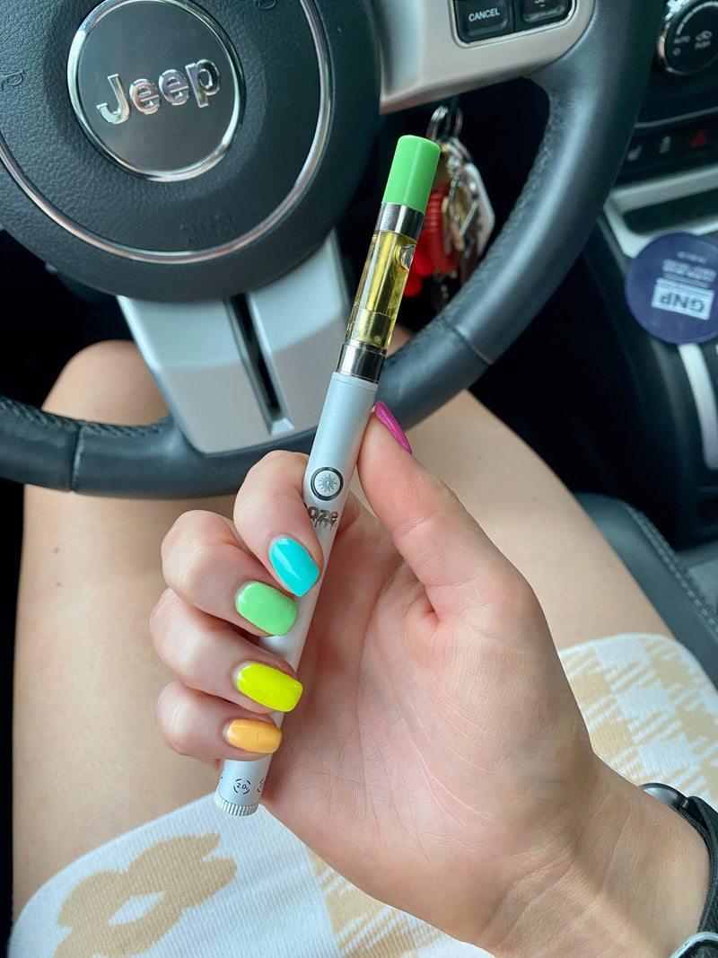 Hand with colorful nails holding white Twist Slim 2.0 Vape Pen Battery with cartridge and mouthpiece
