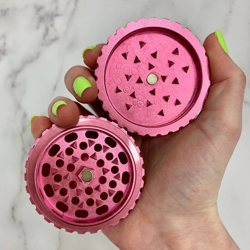 Holding two halves of a pink saturn globe grinder to show the teeth