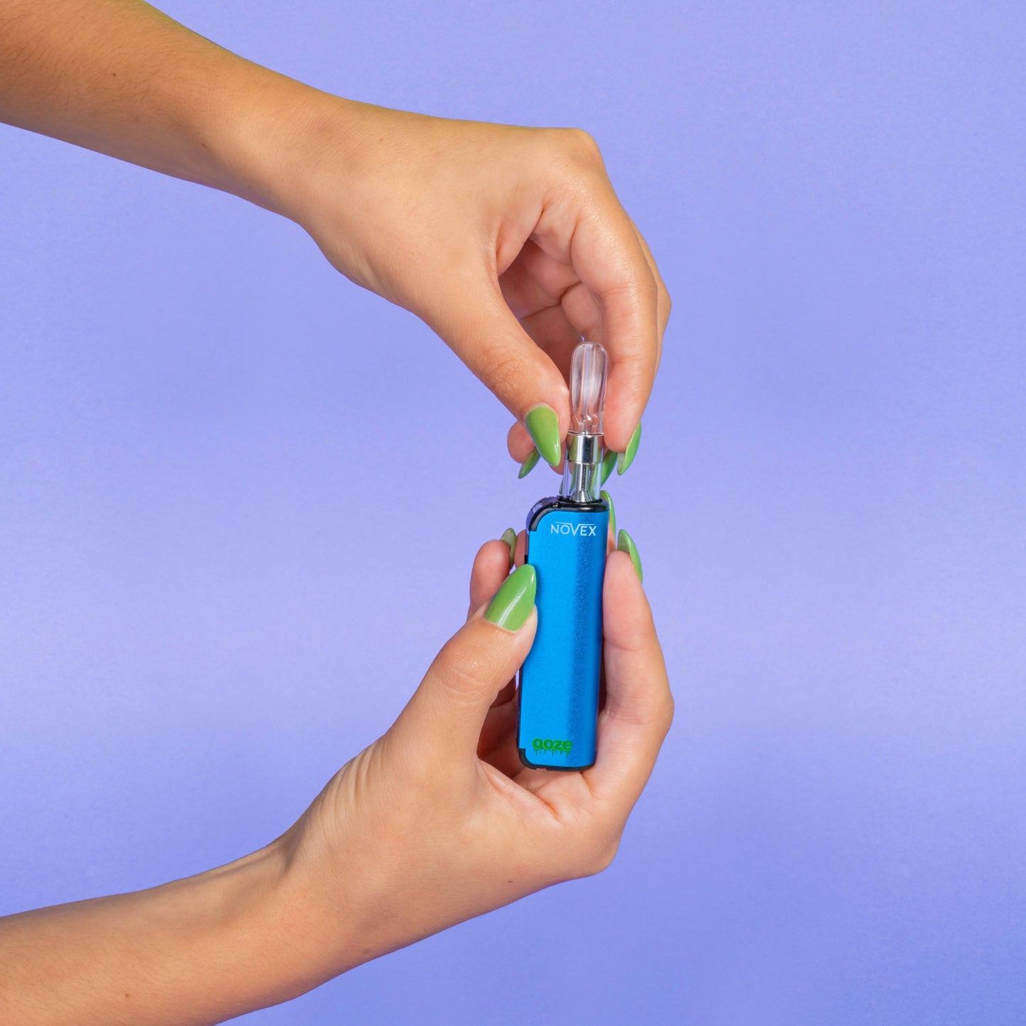 A girl with green nails is screwing a 510 cartridge into a blue Ooze Novex