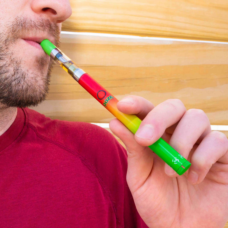 Taking a puff from a rasta color Twist Slim Pen 2.0
