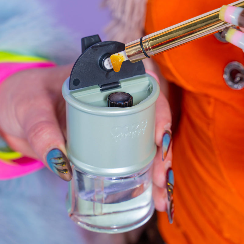 Loading a dab into the sage green Ooze Electro Barrel e-rig with a gold Hot Knife
