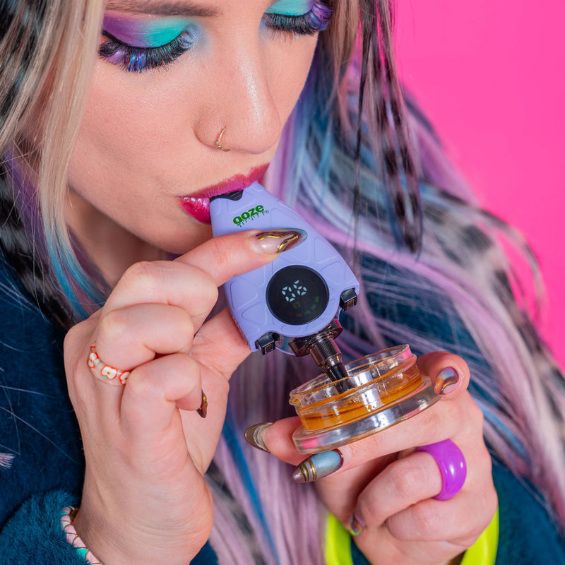 Person using a purple Hover dab straw with a pink background