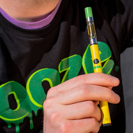 Holding a yellow Twist Slim Pen 2.0 with a green-tipped 510 cart