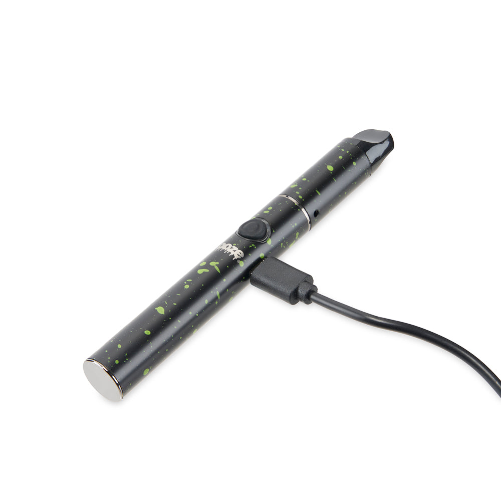 The Green Splatter Ooze Signal wax pen is laid flat with the charger inserted against a white background.