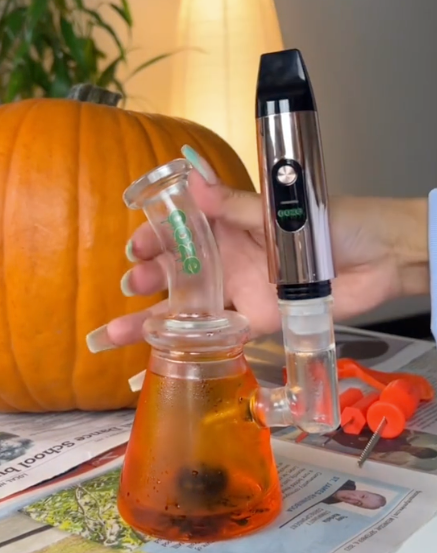 Person attaching the Rose Gold Booster extract vape to dab rig
