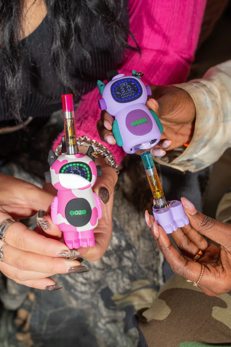 Two people holding Ooze Bot's showing the different ways to use a cartridge with it