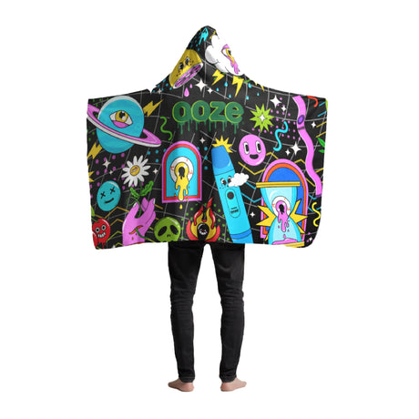 The Ooze Time Warp Beach Blanket is draped over a guy wearing black jeans. He is wearing the hood and has his arms extended to show the entire design