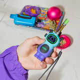 Hand holding a moonrise Bot device with a background of various items on a white surface