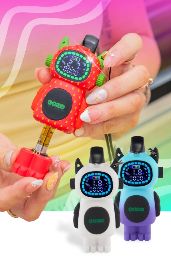 A person pulls the feet out of a Strawberry Bot vape to show the cartridge inside, while a white and moonrise bot are standing in the right corner