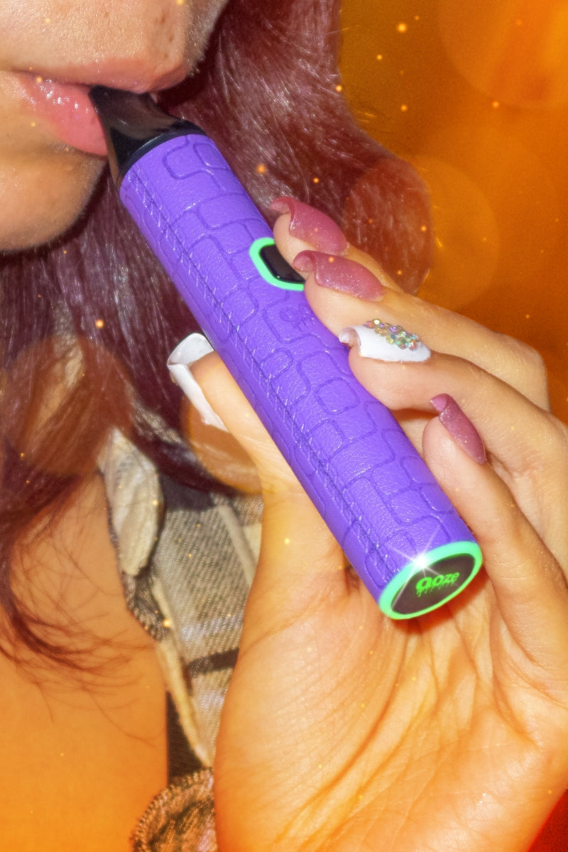 Close up of a girl taking a puff from a purple Ooze Pinch dry herb vape pen