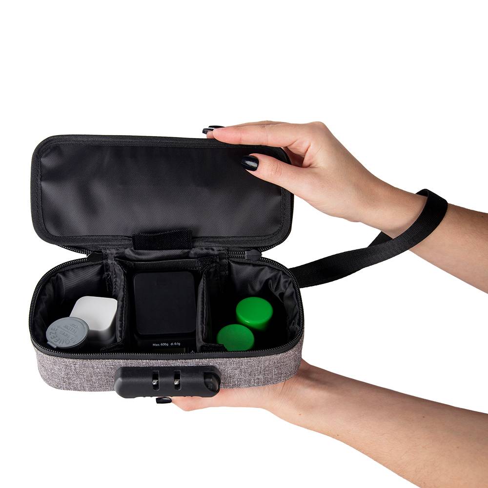 A girl with black nails holds a smoke grey Ooze travel kit open to show the variety of storage containers and small Truweigh scale stored inside