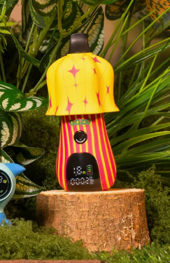 Mushroom shaped device with start and stripe circus pattern, placed on a wooden stump with green foliage in the background.