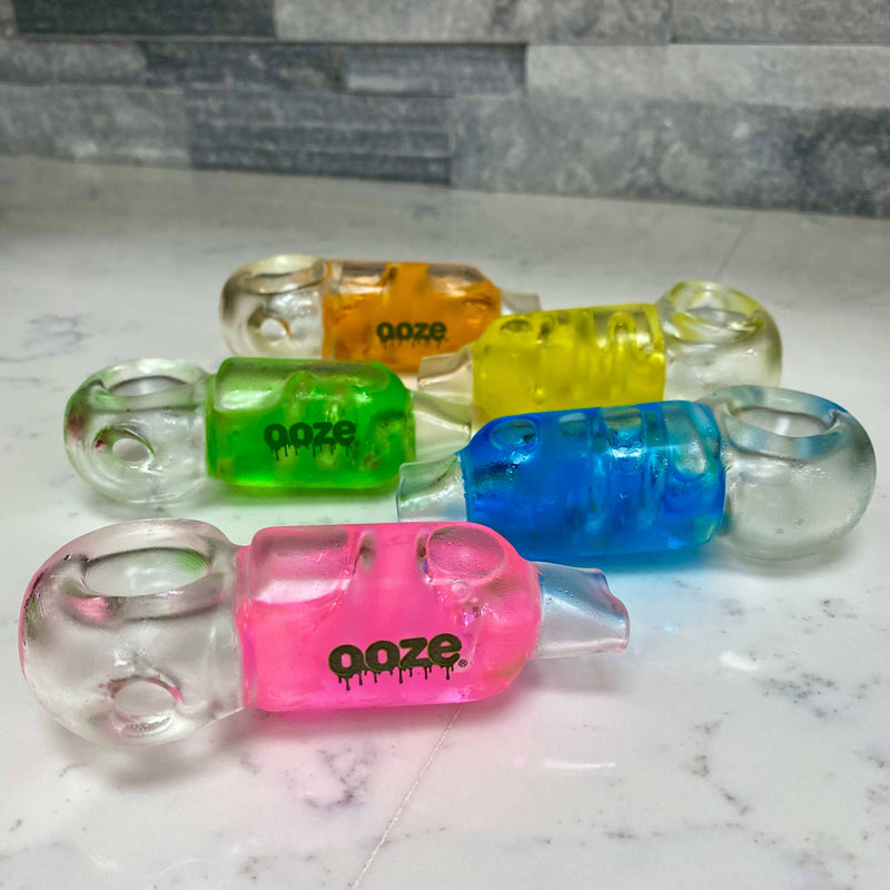 Colorful Ooze cryo freeze pipes on a marble surface with a stone wall background.