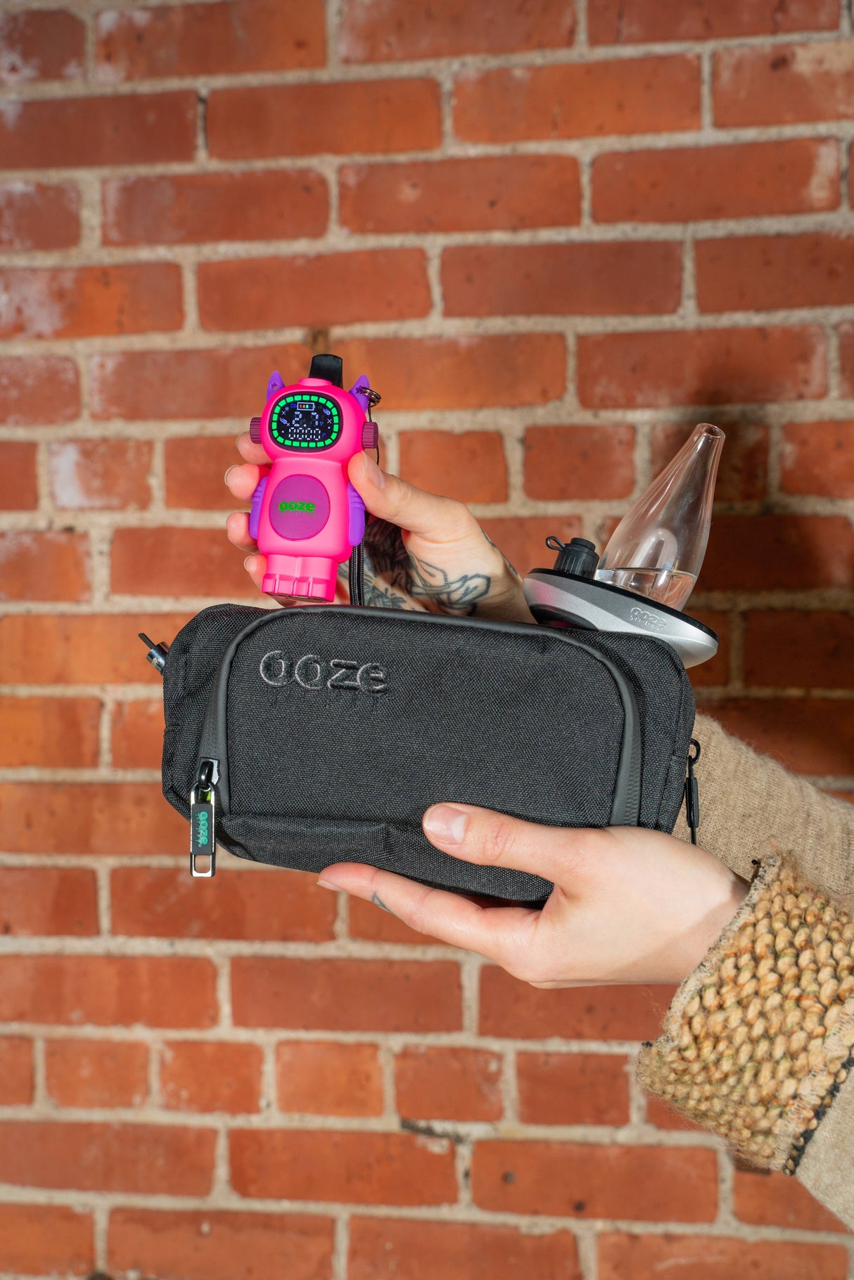 Holding an Atomic pink Ooze Bot character vape battery above a travel pouch