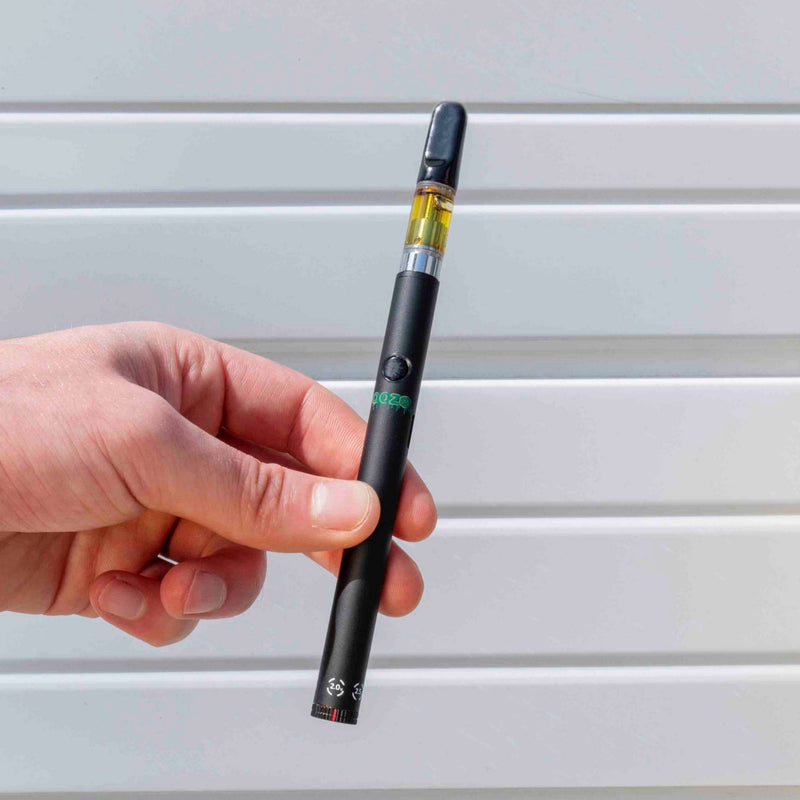 Holding a black Twist Slim Pen 2.0 vape battery
