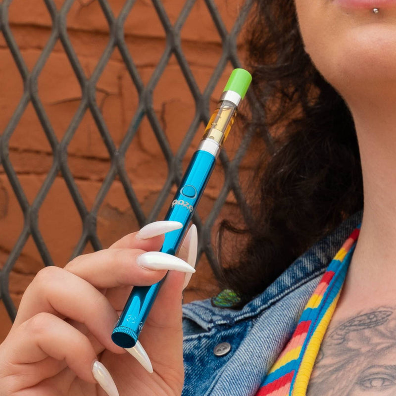Holding a blue Twist Slim Pen 2.0 vape battery