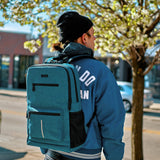 Person wearing a blue backpack with a blurred urban background