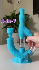 A hand grabs the blue Ooze Echo silicone and glass water pipe on a white table with a plant in the background