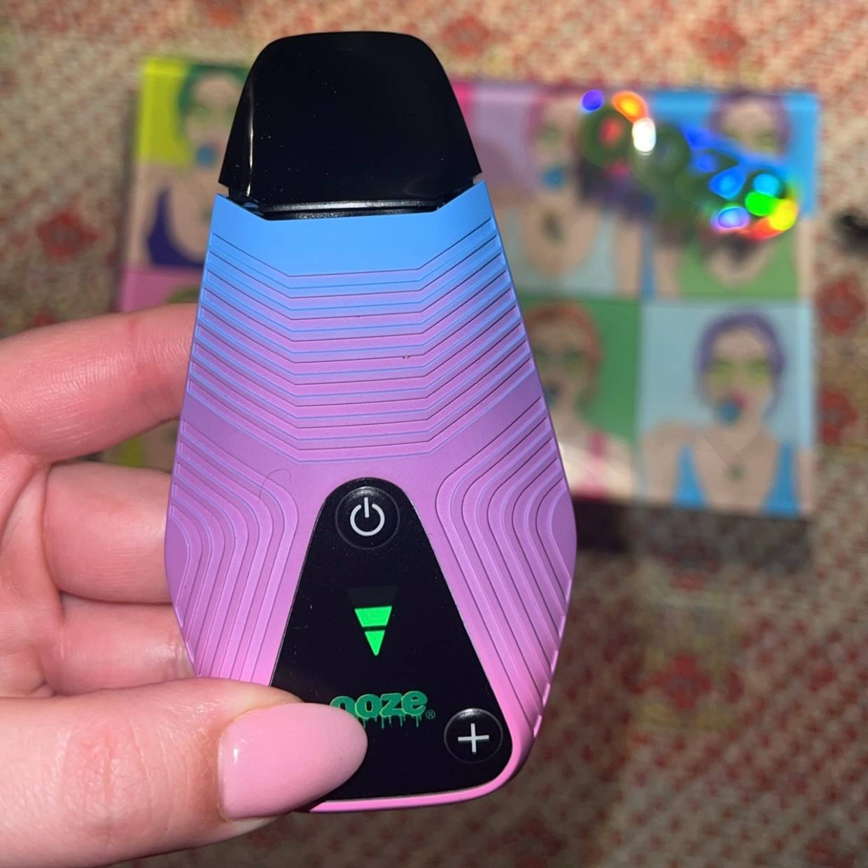 Person holding Brink purple and blue dry herb vaporizer up 
