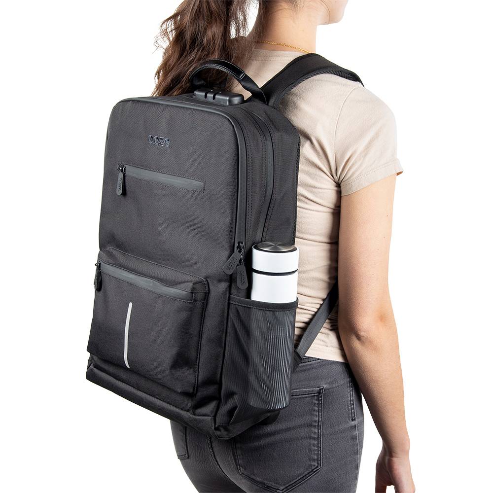 A girl wearing the black Ooze backpack with a white water bottle in the side pocket