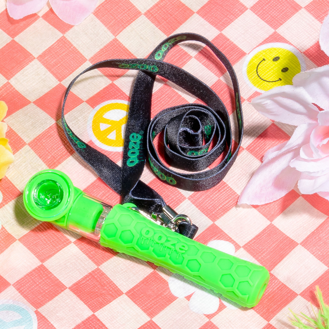 Green Piper with black lanyard laying on checkered blanket