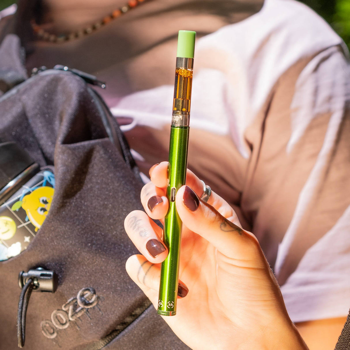 Holding up a green Twist Slim Pen 2.0 vape battery outside
