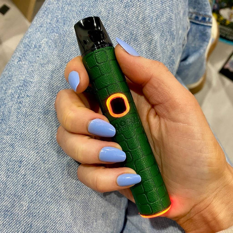 Person holding a green Pinch dry herb vape in front of their blue jeans