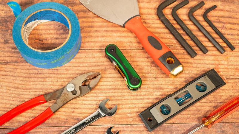 Green Hinge folded up in the center of a wooden table full of tools