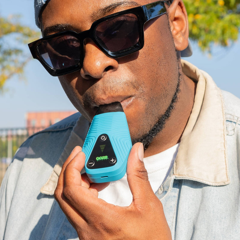 Taking a puff from the sapphire blue Brink dry herb vape