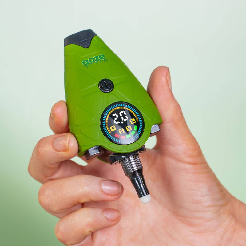 Holding up a green Hover device that is turned on, cap removed to show the quartz tip