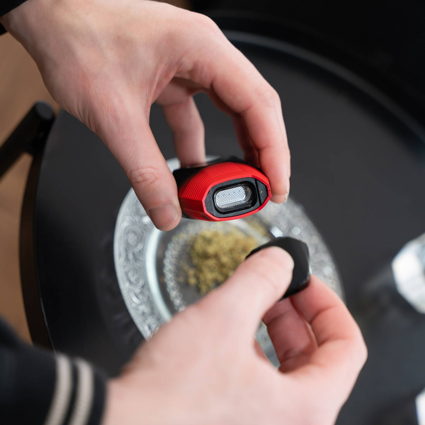 Pulling the cap off a Midnight Sun Brink dry herb vape