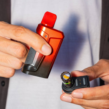 Close up of hands holding a red and black Ooze Duplex 2 vaporizer with the base pulled out to show a dab in the onyx atomizer bucket