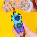 Twisting a 510 cartrige onto the top of a blue and purple Ooze Bot character vape against a yellow background