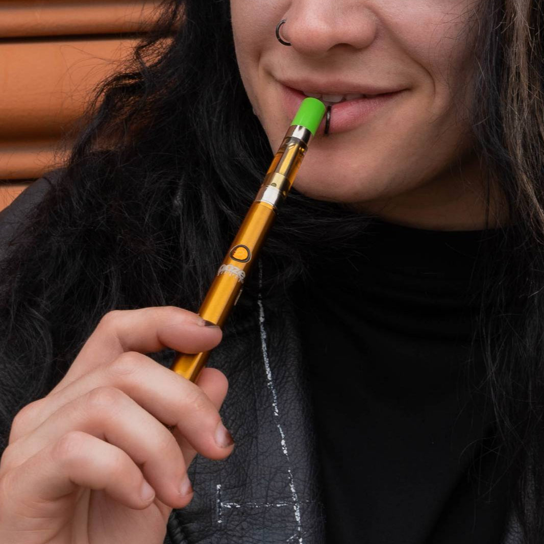 Taking a puff from an orange Twist Slim Pen 2.0 vape battery