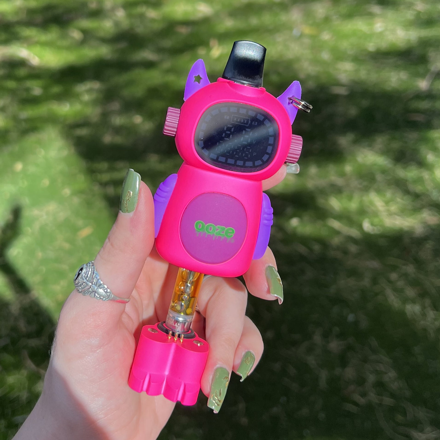 Holding the Atomic pink Ooze Bot character vape battery outside
