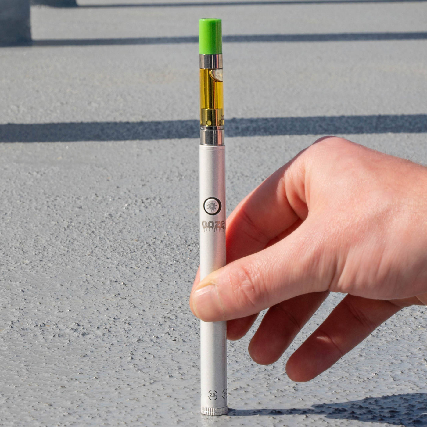 Setting a polar pearl Twist Slim Pen 2.0 vape battery straight down on the ground