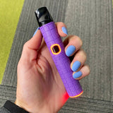 Hand holding a purple Pinch dry herb vape pen with textured grip and black top, against a gray background.