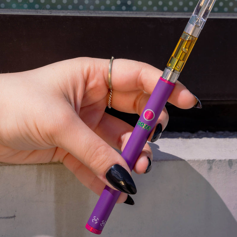 Holding a purple Twist Slim Pen 2.0 vape battery