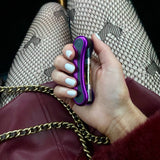 Person holding a purple Hinge battery, folded up against her leather coat and tights