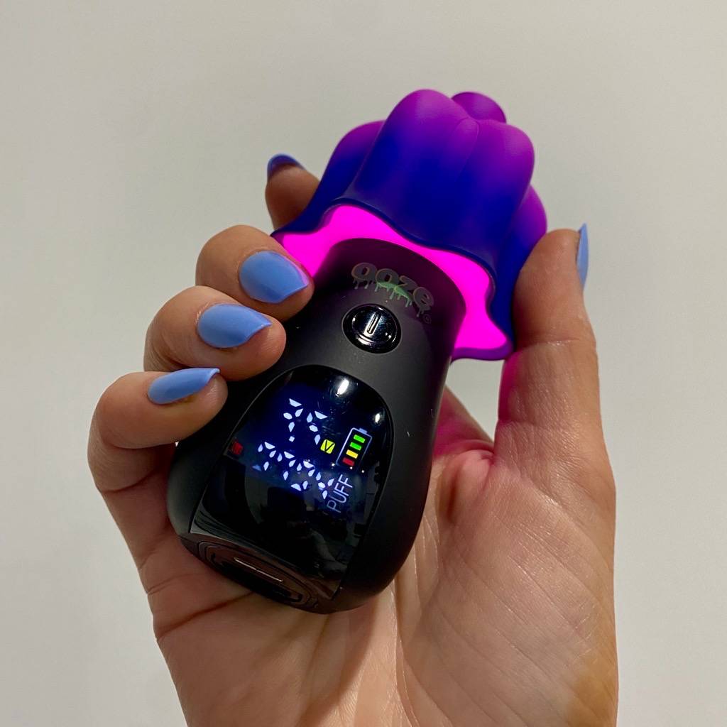 Hand holding purple and black Ooze Shroom vape with digital screen and LED lights on
