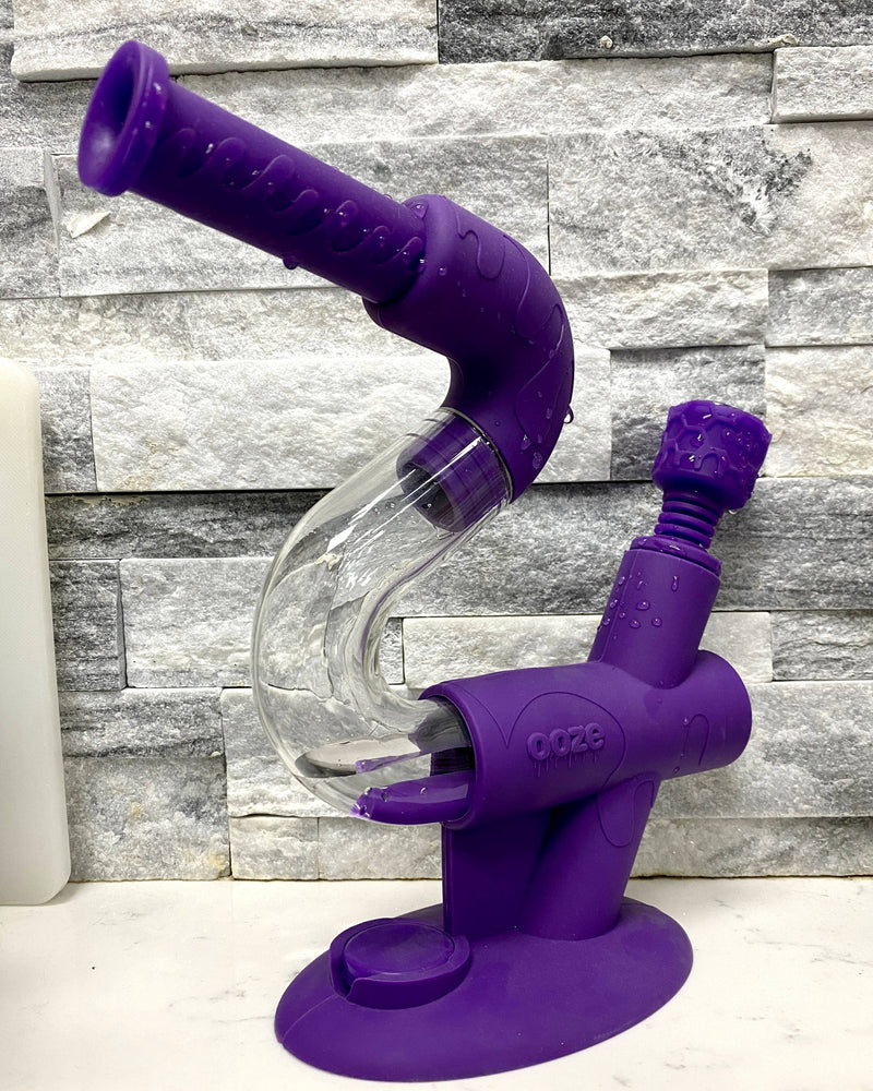 A purple Ooze Swerve silicone pipe is shown filled with water with the Armor bowl inserted against a gray tile background