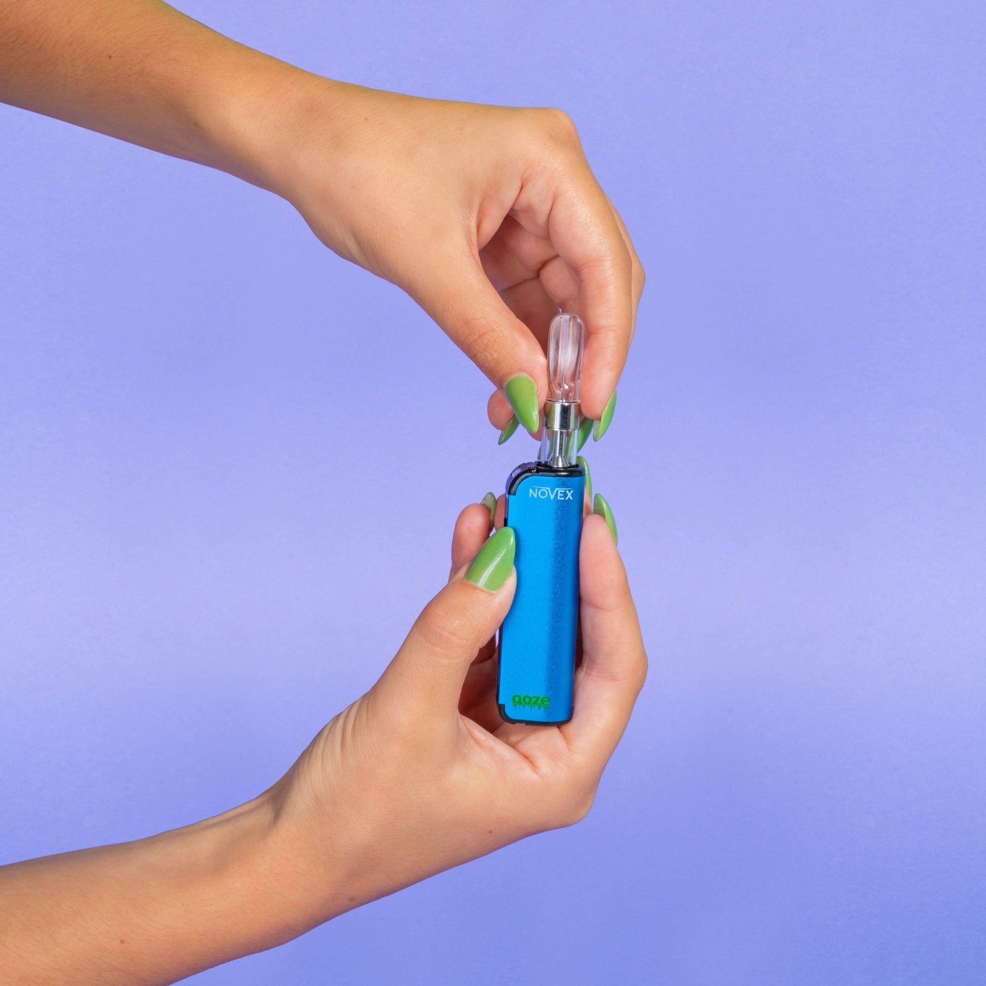 A girl with green nails screws a 510 cartridge into a blue Ooze Novex